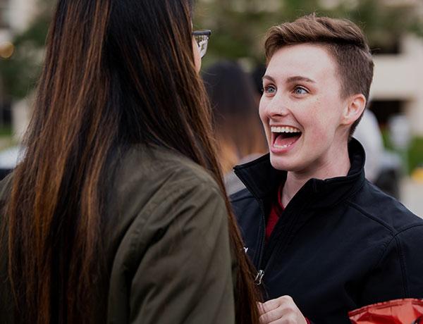 Two females talking and smiling.